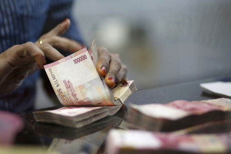 A teller counts Indonesian Rupiah notes inside a money changer